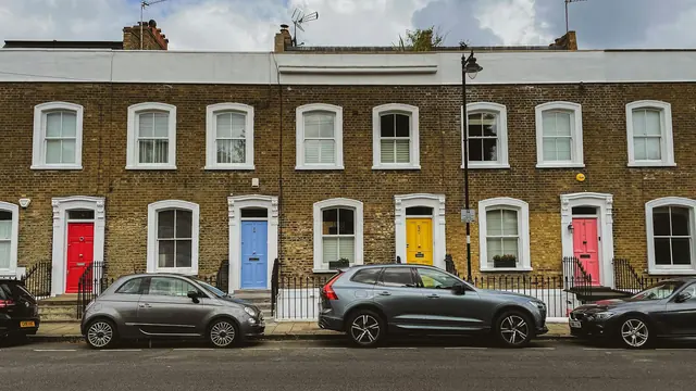 A terrace of brick houses with brightly painted front doors on an English street